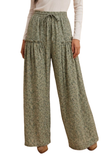 A person wearing high-waisted, wide-leg pants with a small-scale green and beige floral print, paired with a white long-sleeve top. The photo is cropped from the chest down against a plain white background.