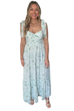 woman wearing a sage green floral maxi dress with bow-tied straps, a sweetheart neckline, ruched front, and a flowing ruffle hem.