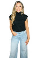 Woman wearing a black short sleeve turtleneck knit sweater top with light blue denim wide leg pants 