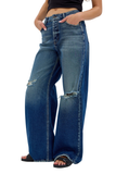 A person wearing high-waisted, wide-leg blue denim jeans with distressed rips at the knees and thighs, paired with black slide sandals against a plain white background.