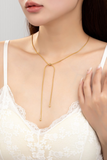 woman wearing a gold snake chain lariat necklace with a gold bead slider. 
