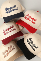 5 panel, 2 toned trucker hats that have "Sorry About My Husband" embroidered to match the bill of the hat. The photo has 5 hats that are all ivory with a different color bill. Color if hat bills are from top to bottom: navy, red, maroon, black and tan