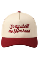 5 panel 2 tone (ivory and maroon) trucker style hat that has "Sorry About My Husband" Embroidered on the front. The embroidery is in maroon stitching that matches the bill.