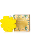 A yellow flower-shaped sponge bath bomb shown next to its illustrated packaging box on a clean white background.