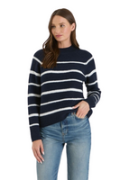 woman wearing a navy high-neck sweater with white stripes. sweater is paired with light blue jeans 