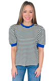 A woman modeling a short-sleeve top with horizontal black and white stripes and solid blue trim on the crew neck and sleeve cuffs, paired with blue jeans against a plain white background.