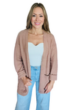 Girl wearing a mocha colored chevron textured cardigan. Cardigan is oversized and has pockets.