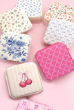 Floral and patterned travel jewelry organizer cases on pink background