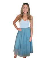 Woman wearing a white cami tank top with a dusty blue tulle midi a-line style skirt 