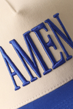 Close-up of a cap with 'AMEN' embroidered in blue on a beige and blue background