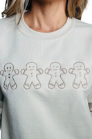 Upclose photo of a tan sweatshirt with 4 embroidered gingerbread cookies on the front center 