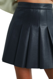 Close-up view of a black pleated faux leather mini skirt with a high-waist design, showing the structured pleats and smooth leather texture.