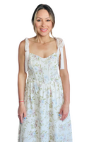 Woman wearing a maxi dress with a floral print. Dress has a corset style top with satin tie straps