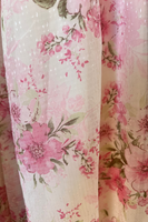 Upclose photo of fabric/floral detail. Pink flowers with green leaves/stems