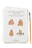 A stack of Emily Lex Studio paintable watercolor notecards with four holiday gingerbread illustrations on the top card, shown next to a wooden paintbrush on a white background.