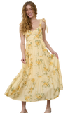Model in a yellow floral midi dress with lace tie straps, holding the skirt