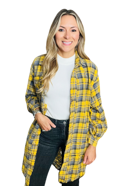 woman wearing an oversized tartan plaid flannel shirt. Flannel is yellow, white and black. Flannel is styled with a white shirt and black denim pants