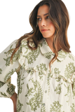 Close up of a cream and olive green floral babydoll blouse featuring a rounded Peter Pan collar, ruffle trim detail, long puff sleeves, and lightweight textured gauze fabric.