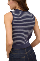 woman wearing a navy blue button-down sweater vest with white stripes. Sweater is paired with dark blue denim 