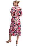 A woman modeling a short-sleeve midi dress with a high mock neck and a vibrant floral print, shown from the back against a plain white background.
