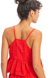 A woman shown from the back wearing a bright red spaghetti-strap dress with a textured lace-like bodice and a ruffled peplum hem, against a plain white background.