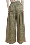A pair of wide-leg cropped pants with a textured, speckled olive green and beige pattern, featuring an elastic waistband and side pockets, shown on a model from the back.