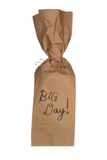 A brown kraft paper gift bag tied with a red-and-white string, printed with the words 'Big Day!' in black script on a plain white background.