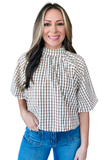 A woman wearing a brown and white gingham check blouse with puff sleeves and a high gathered neckline, paired with blue jeans, against a plain white background.
