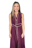A woman modeling a sleeveless, button-front maxi dress in deep plum purple with white piping details, set against a plain white background.