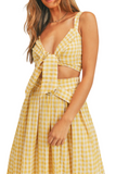 Upclose photo of a woman wearing a yellow gingham pattern set. Set is a cropped top that ties in the front with a midi skirt that has a belt 