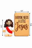 A small figurine of Jesus beside a rectangular wooden sign with the engraved text 'EVERYONE NEEDS A LITTLE Jesus.' Arrows and labels indicate dimensions: 1.