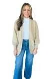 Front view of the Bundle Up Mallard Cardigan Sweater in cream, featuring an open-front design, relaxed fit, and voluminous long sleeves, styled with a white mock neck top and wide-leg jeans.