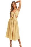 woman wearing a yellow gingham pattern set. Set is a cropped top that ties in the front with a midi skirt that has a belt 