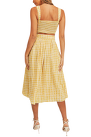 back of a woman wearing a gingham yellow print top and skirt set. Top has a smoked back and the skirt is a midi length 