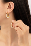 Woman holding a hoop earring that has pearls wire wrapped on the hoop earring. The other earring is on the woman's ear. 