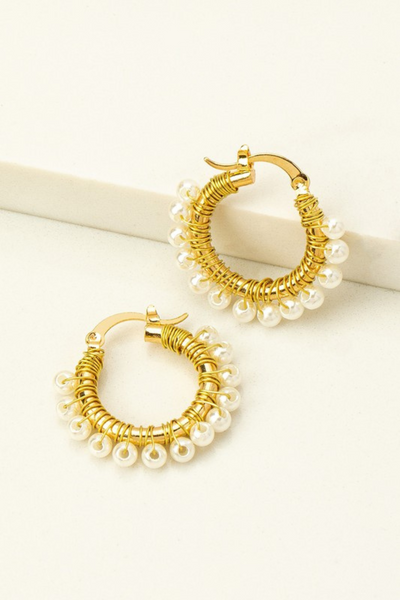 Upclose photo of gold hoop earrings with gold wire wrapped pearls. Hoops have a latch closure 