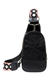 Black faux leather crossbody sling bag, part of the white, black, pink and turquoise aztec patterned guitar strap shown.