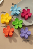 Bright colored daisy hair claw clips on a white and tan background. Colors include: yellow, blue, red, green, orange and lavender
