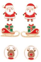 White background with enamel Christmas stud earring trio set. Earrings include a full body Santa,a red sled with a green present with a red bow, white circle with Rudolph reindeer with a red collar  