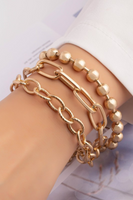 Chunky Gold Three Chain Bracelet Set on a wrist. First row is a textured link chain, second chain is a flat link chain, the third chain is a thick gold ball chain. 