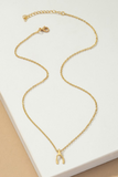 Dainty gold chain with a gold wishbone charm. Necklace is 18 inches with a 3 inch extender. Necklace is on a white tile on a tan background