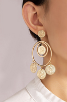 Gold coin and double hoop drop earrings with dangling gold coin charms. Earrings are shown on a woman's ear. 
