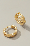 unclose picture of braided gold huggie style hoop earrings. One earring is laying flat and the other earring is sitting upright.