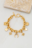 Gold chain bracelet with gold charms and a toggle closure. Charms include crescent, star, coin, butterfly, triangle, and circle