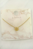 Photo of a delicate gold necklace with a dainty gold compass charm attached> necklace is on a jewelry card
