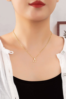 Woman wearing a dainty chain necklace with a gold wishbone charm