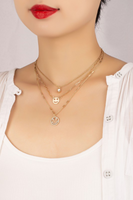 Three piece gold layered necklace set featuring smile face charms. The necklace is photographed on a woman's neck. 