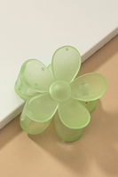 Up close photo of a frosted lime green daisy hair claw clip on a white and tan background