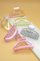 Iridescent pastel colored crescent shaped hair claw clips arranged on a tan and white background. Colors of hair claws include: yellow, orange, light green, blue, lavender, and pink 