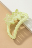 Semi transparent light green colored crescent shaped hair claw with a light green polkadot pattern.  Hair claw has 2 flowers at the top of the crescent hair claw.